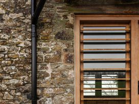 A window with wooden slats and stone wall at Lower Walreddon Farm in Tavistock