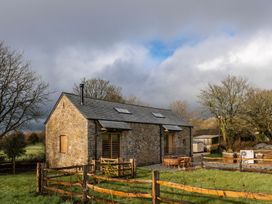A building with a stone exterior and wooden fence at Lower Walreddon Farm in Tavistock