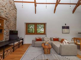 A living room with a stone wall and sofa at Lower Walreddon Barn Tavistock