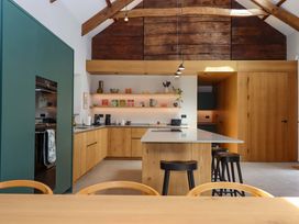 A kitchen with a central island and wooden shelves at Lower Walreddon Barn in Tavistock