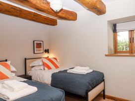 A bedroom with two beds and a window at Lower Walreddon Barn Tavistock