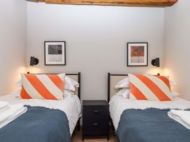 A bedroom with two beds and a nightstand at Lower Walreddon Barn in Tavistock