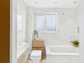 A bathroom with a bathtub, toilet, and sink at 59a Gwscwm Road