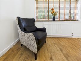 An armchair near a window with a vase of flowers at 59a Gwscwm Road