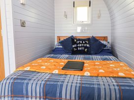 A bedroom with a bed, pillows, a blanket and a tablet at Honeypot Hideaways - Manuka