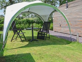 An outdoor seating area with a canopy, table and chairs at Honeypot Hideaways - Manuka