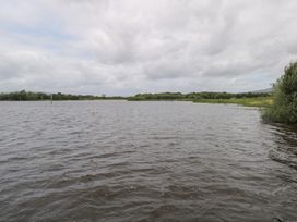 A body of water with surrounding greenery and cloudy sky at The Cottage in Ballinagleira