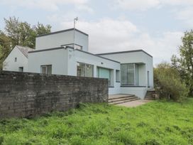 A house with a wall and grass in the yard at The Cottage in Ballinagleira