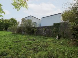 A view of buildings with a wall and greenery at The Cottage in Ballinagleira