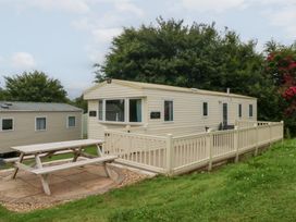 A mobile home with a deck and table at Mountain View in Pwllheli