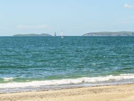A beach with sailboats and islands in the background at Mountain View Haven/Hafan Y Mor near Pwllheli