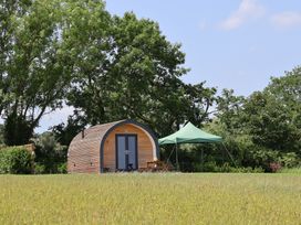 A wooden cabin with a tent and furniture on a grassy area at Honeypot Hideaways - Clover