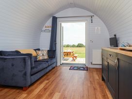 A living room with a sofa and door leading to an outdoor area at Honeypot Hideaways - Clover