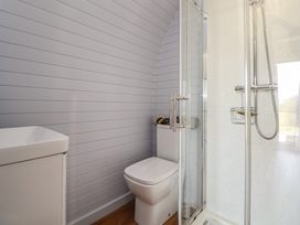 A bathroom with a shower, toilet, and sink at Honeypot Hideaways - Clover