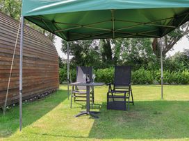 A garden area with a table and chairs under a gazebo at Honeypot Hideaways - Clover