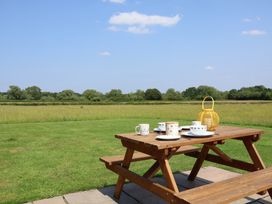 A picnic table with cups and plates in a field at Honeypot Hideaways - Clover