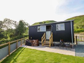 A hot tub and seating area outside a cabin at Charollais in Oswestry