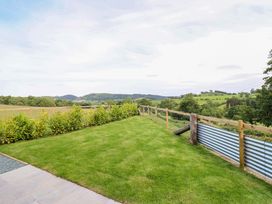 A garden with a lawn and fence overlooking hills at Charollais in Oswestry