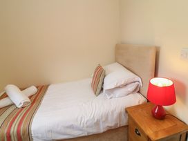 A single bed with pillows and a bedside lamp at Lodge 9 Brigg