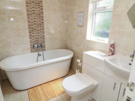 A bathroom with a bathtub, toilet, and sink at Lodge 13 Brigg