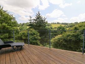 A deck with a chair overlooking trees at The Old Barn in Ciliau Aeron near Aberaeron
