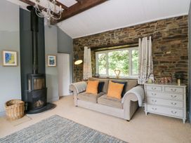 A living room with a sofa and wood stove at The Old Barn in Ciliau Aeron near Aberaeron