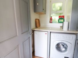 A laundry room with a washing machine and fridge at The Old Barn in Ciliau Aeron near Aberaeron