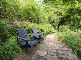 A garden with chairs and a stone path at The Old Barn in Ciliau Aeron near Aberaeron