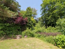 A garden area with greenery and a stone bench at The Old Barn in Ciliau Aeron near Aberaeron