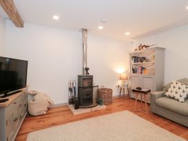 A living room with a stove and television at The Threshing Barn in Chipping Norton