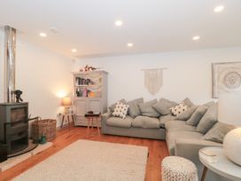 A living room with a sofa, fireplace, and bookshelf at The Threshing Barn in Chipping Norton