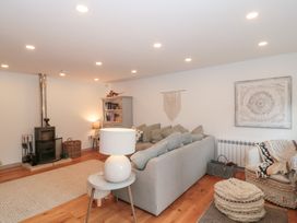 A living room with a sofa, fireplace, and bookshelf at The Threshing Barn in Chipping Norton