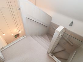 A staircase with a handrail and glass panel at The Threshing Barn in Chipping Norton