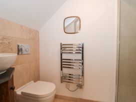 A bathroom with a toilet, hand basin, towel radiator and a mirror at The Threshing Barn Chipping Norton