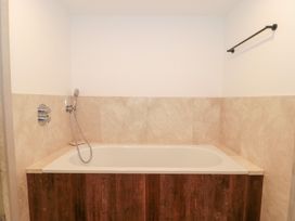 A bathtub with a showerhead in a bathroom at The Threshing Barn in Chipping Norton