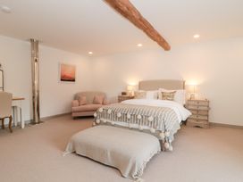 A bedroom with a bed, sofa, desk, and chair at The Threshing Barn in Chipping Norton