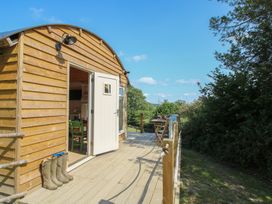 A wooden cabin with a deck and furniture at Squirrel's Drey Chapel Lawn near Clun