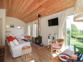 A living room with a sofa, bed, and fireplace at Squirrel's Drey in Chapel Lawn near Clun