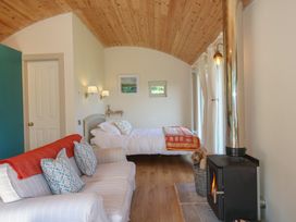 A bedroom with a bed and sofa at Squirrel's Drey in Chapel Lawn near Clun