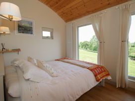 A bedroom with a bed and windows at Squirrel's Drey Chapel Lawn near Clun