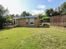 A wooden cabin with a deck and fence at Squirrel's Drey, Chapel Lawn near Clun