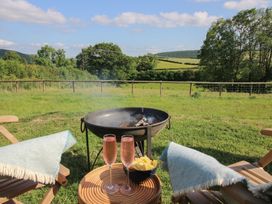 A fire pit with drinks and snacks in a garden at Squirrel's Drey in Chapel Lawn near Clun