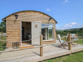 A wooden cabin with a deck and chairs at Owl's Hollow in Chapel Lawn near Clun