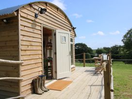 A wooden cabin with a deck and chairs at Owl's Hollow in Chapel Lawn near Clun