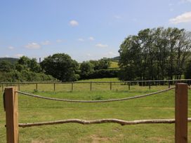 A view of a green field with trees and a fence at Owl's Hollow Chapel Lawn near Clun