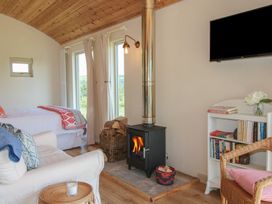 A living room with a stove and bookshelves at Owl's Hollow in Chapel Lawn near Clun
