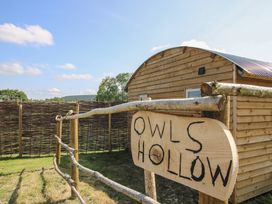 A wooden sign in front of a cabin at Owl's Hollow in Chapel Lawn near Clun