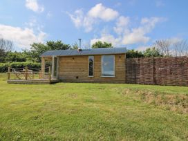 A wooden cabin with a deck in a grassy area at Owl's Hollow Chapel Lawn near Clun