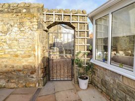 A garden with a stone wall and gate at Linn Cottage in Hexham