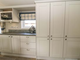A kitchen with cabinets and a microwave at The Beaumont No 34 New Quay